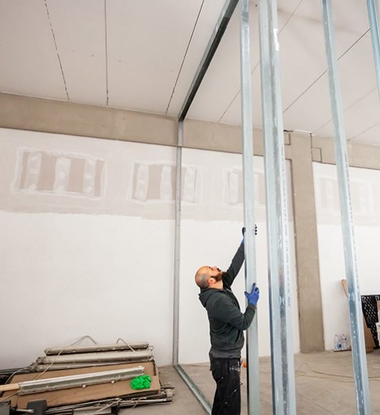 Worker at work in the construction of a plasterboard wall.
